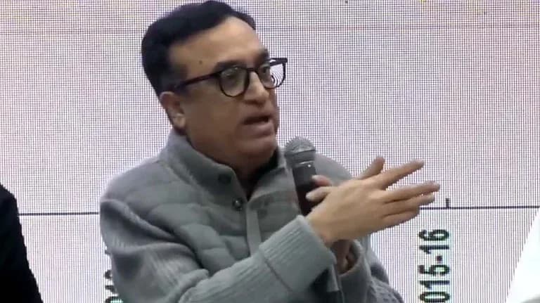 ایک آدمی مائیکروفون پکڑے ہوئے بات کر رہا ہے اور ہاتھ سے اشارہ کر رہا ہے۔